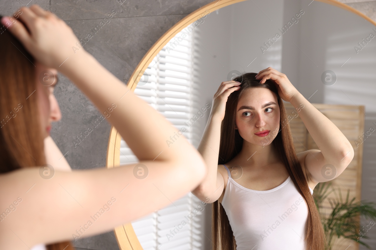 Photo of Beautiful woman with healthy hair roots near mirror at home