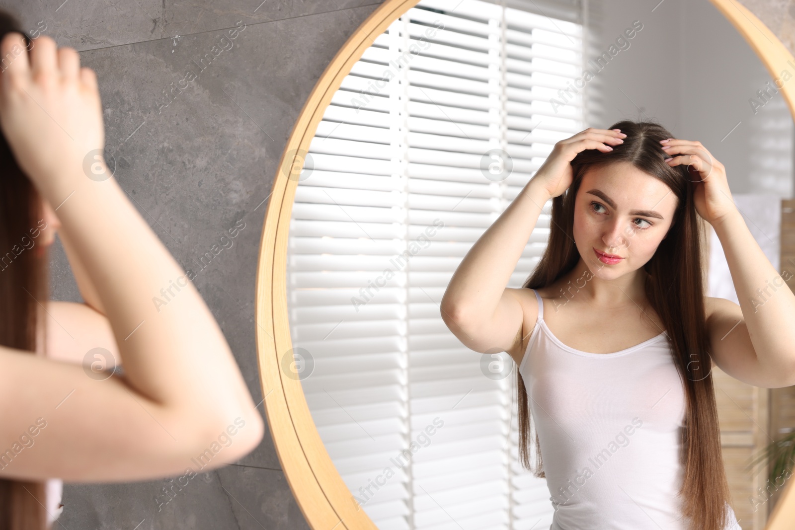 Photo of Beautiful woman with healthy hair roots near mirror at home