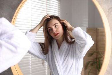 Photo of Beautiful woman with healthy hair roots near mirror at home