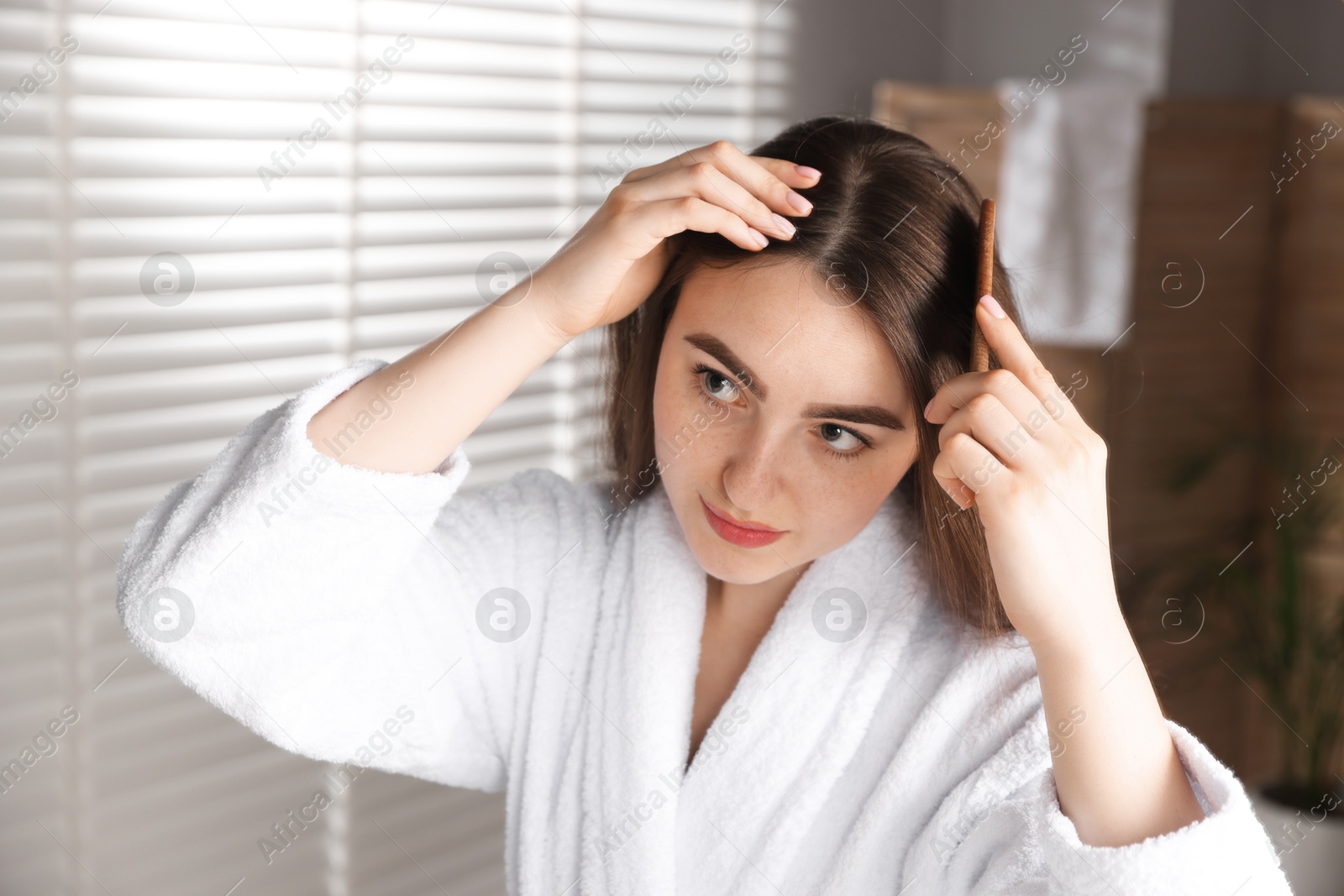 Photo of Beautiful woman combing her hair with healthy roots at home