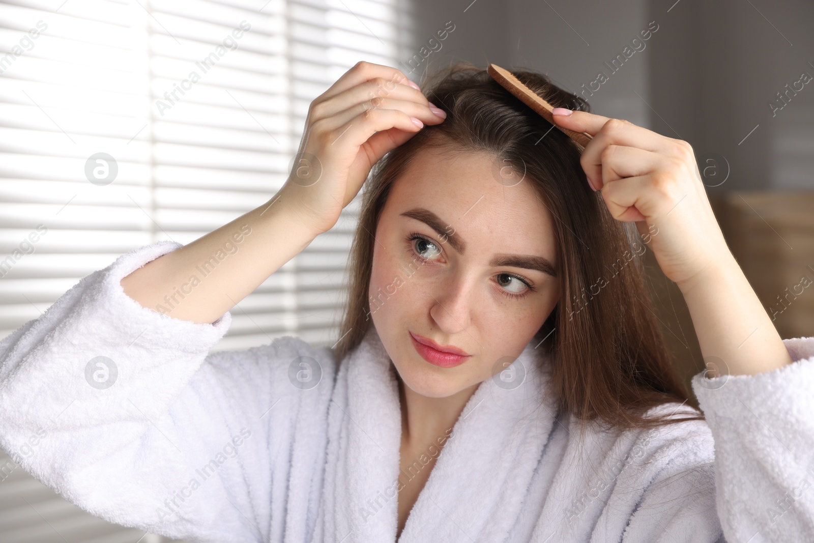 Photo of Beautiful woman combing her hair with healthy roots at home