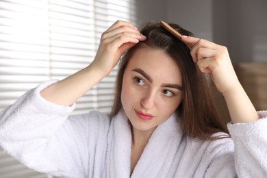 Beautiful woman combing her hair with healthy roots at home