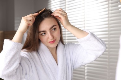 Photo of Beautiful woman combing her hair with healthy roots at home