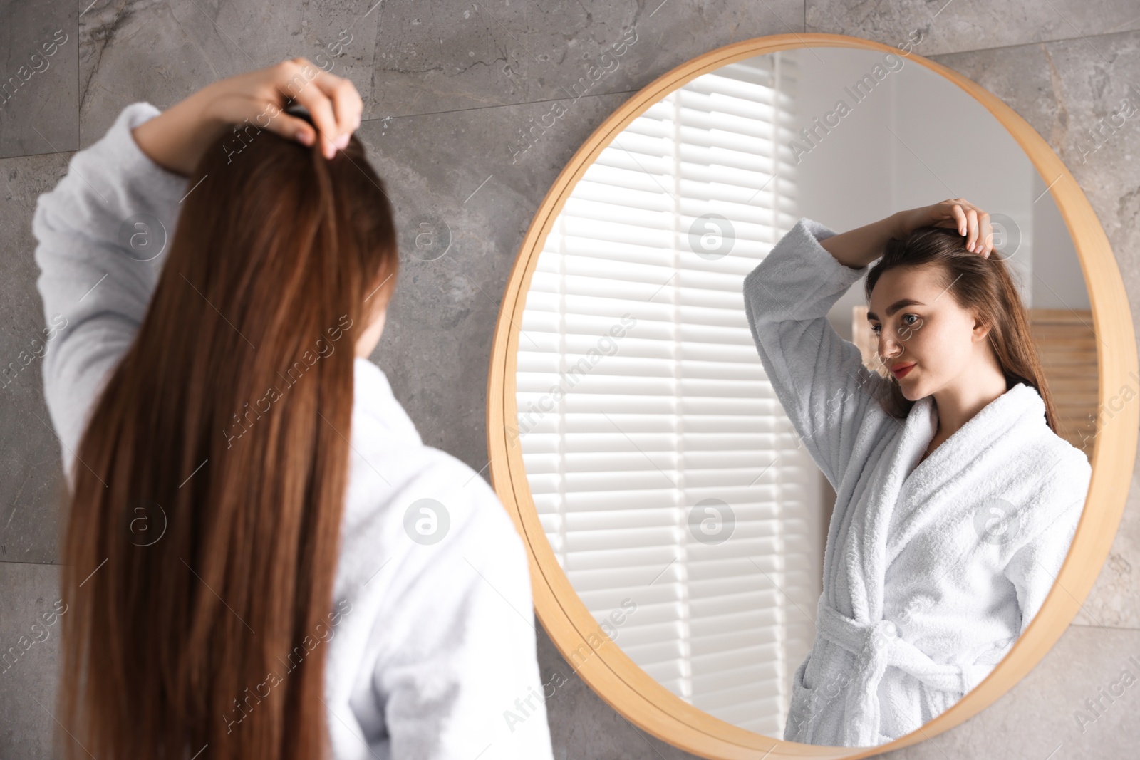 Photo of Beautiful woman with healthy hair roots near mirror at home