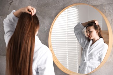 Photo of Beautiful woman with healthy hair roots near mirror at home