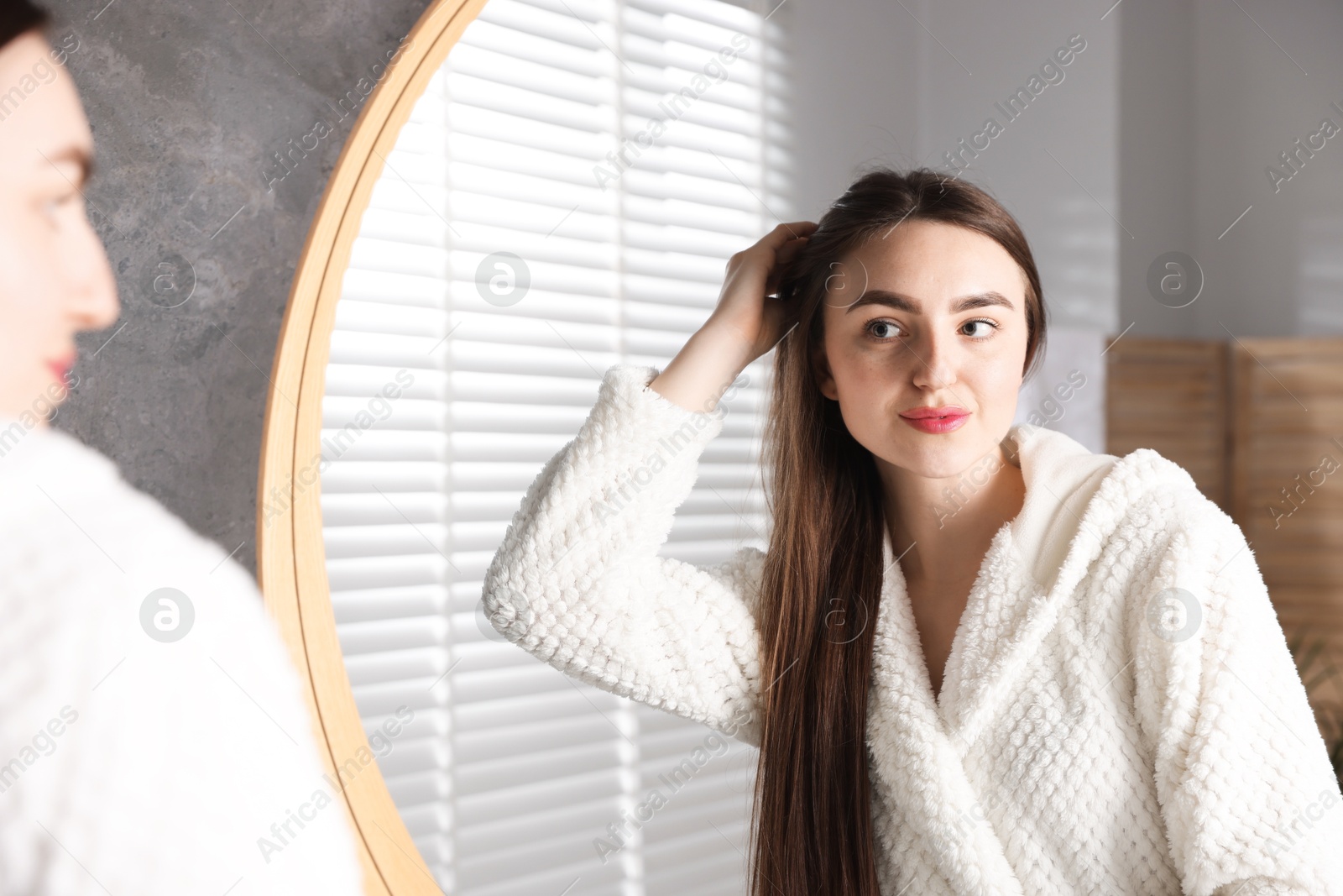 Photo of Beautiful woman with healthy hair roots near mirror at home