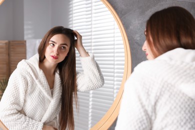 Photo of Beautiful woman with healthy hair roots near mirror at home