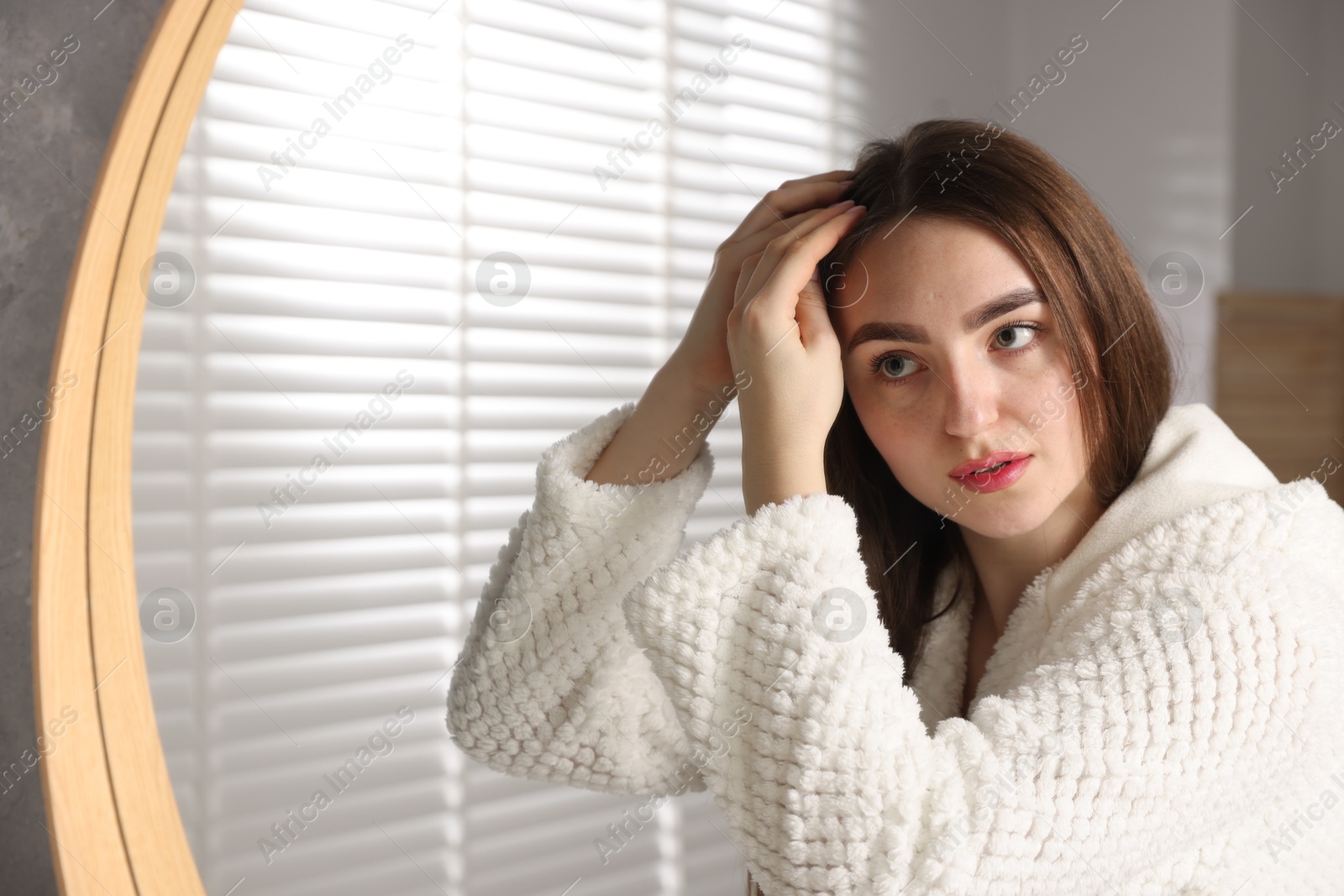 Photo of Beautiful woman with healthy hair roots near mirror at home