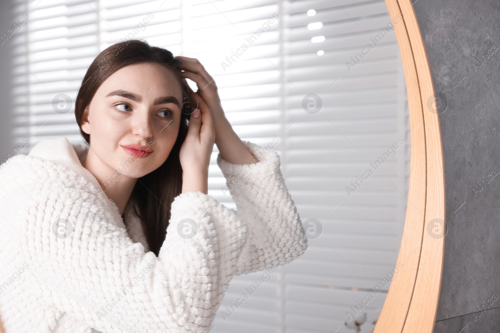 Photo of Beautiful woman with healthy hair roots near mirror at home