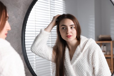 Photo of Beautiful woman with healthy hair roots near mirror at home