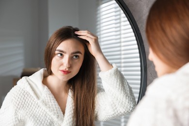 Photo of Beautiful woman with healthy hair roots near mirror at home