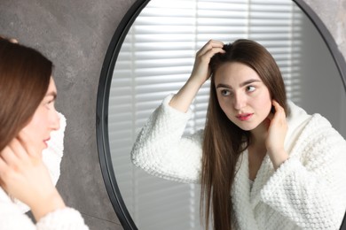 Photo of Beautiful woman with healthy hair roots near mirror at home