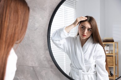 Photo of Beautiful woman with healthy hair roots near mirror at home