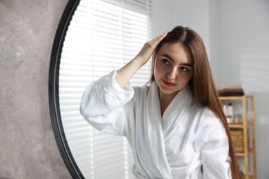 Photo of Beautiful woman with healthy hair roots near mirror at home