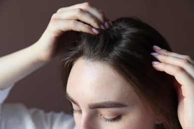 Photo of Woman with healthy hair roots on brown background, closeup