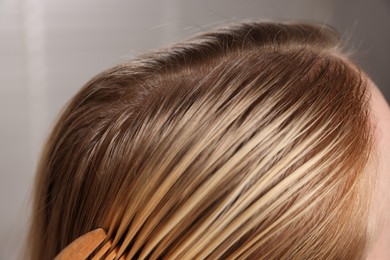 Photo of Woman with undying hair roots on blurred background, closeup