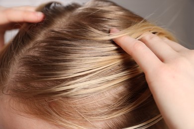 Woman with undying hair roots on blurred background, closeup