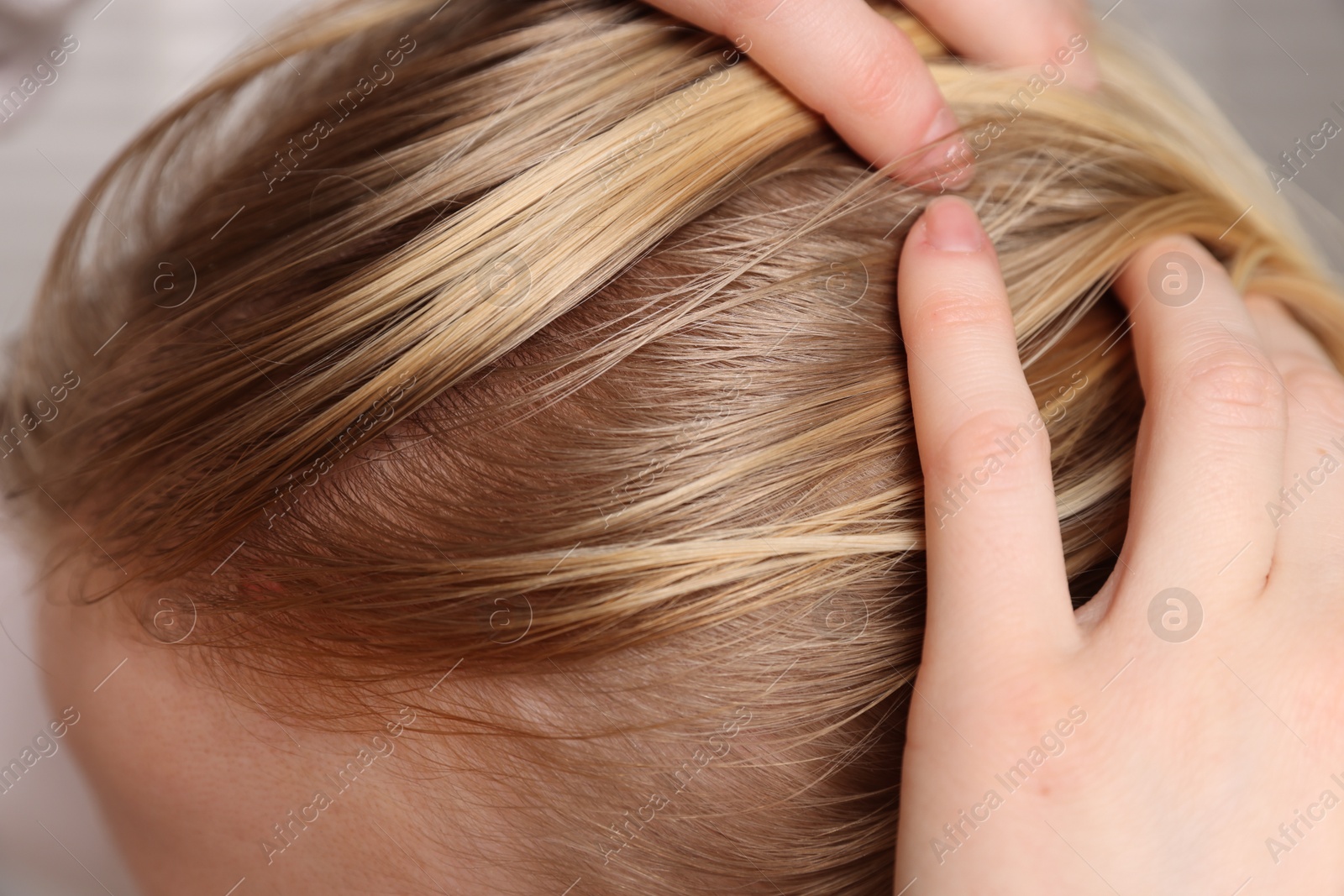 Photo of Woman with undying hair roots on blurred background, closeup