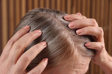 Senior woman with healthy hair roots on blurred background, closeup