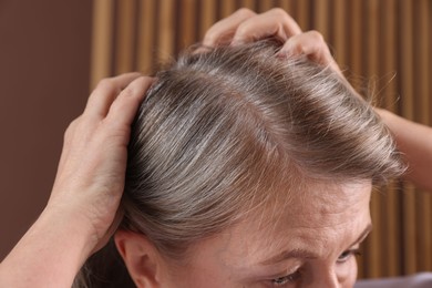 Senior woman with healthy hair roots on blurred background, closeup