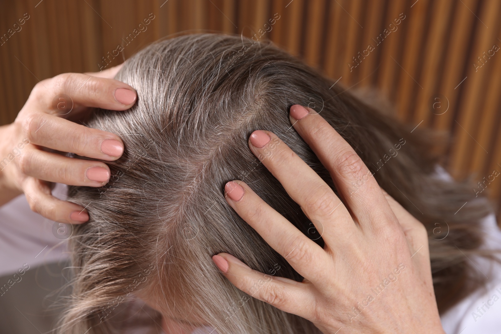 Photo of Senior woman with healthy hair roots on blurred background, closeup