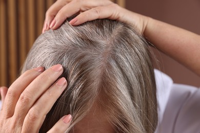 Photo of Senior woman with healthy hair roots on blurred background, closeup