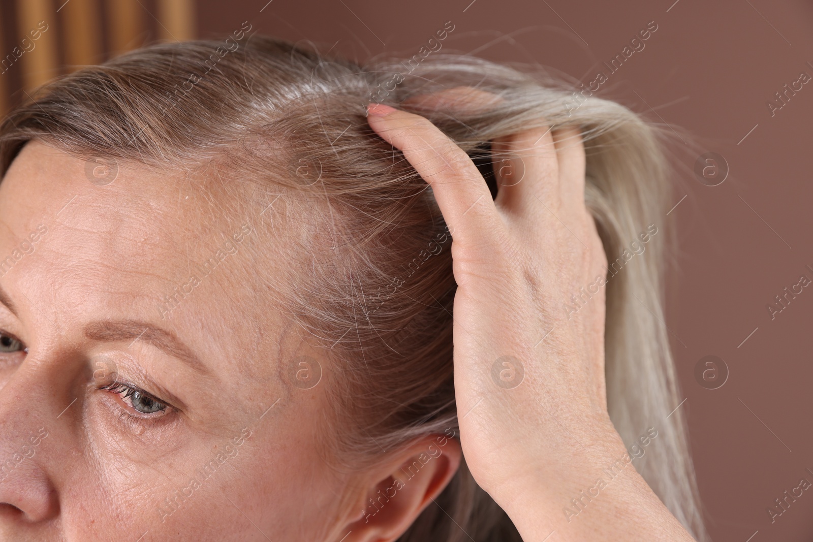 Photo of Senior woman with healthy hair roots on blurred background, closeup