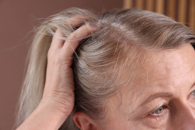 Senior woman with healthy hair roots on blurred background, closeup