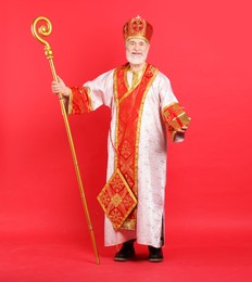 Photo of Saint Nicholas with gift on red background. Space for text