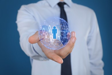 Targeting, recruitment, customer acquisition. Businessman holding virtual globe with human icons against blue background, closeup