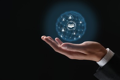 Image of Targeting, recruitment, customer acquisition. Businessman holding virtual globe with human icons against black background, closeup