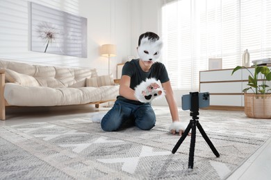 Photo of Quadrobics. Boy in cat mask and gloves recording video at home