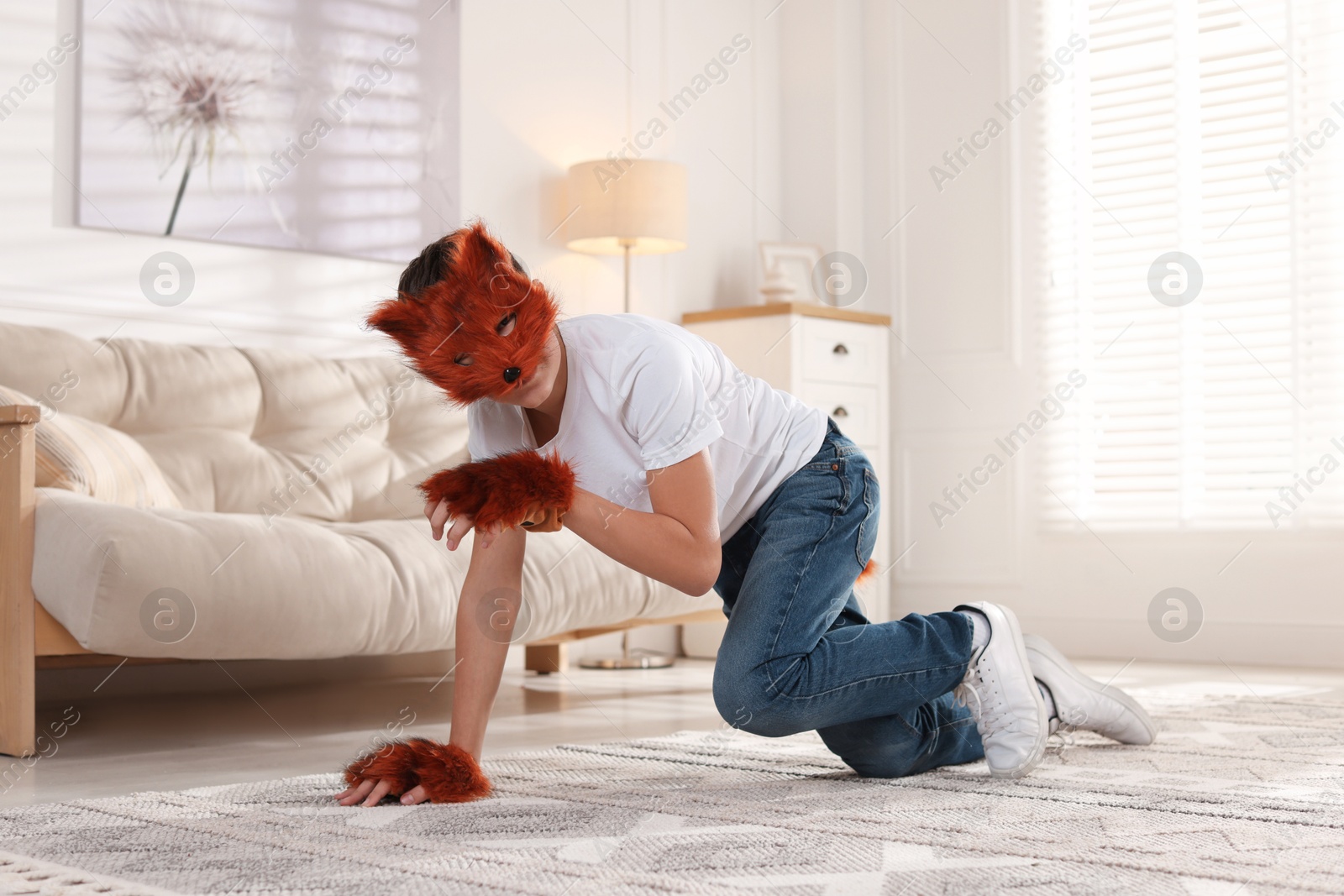 Photo of Quadrobics. Boy wearing fox mask, gloves and tail on floor at home