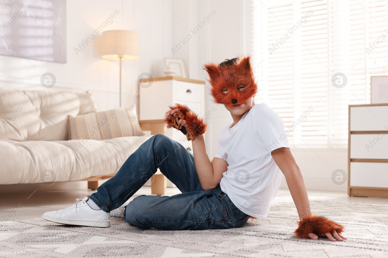 Photo of Quadrobics. Boy wearing fox mask and gloves on floor at home