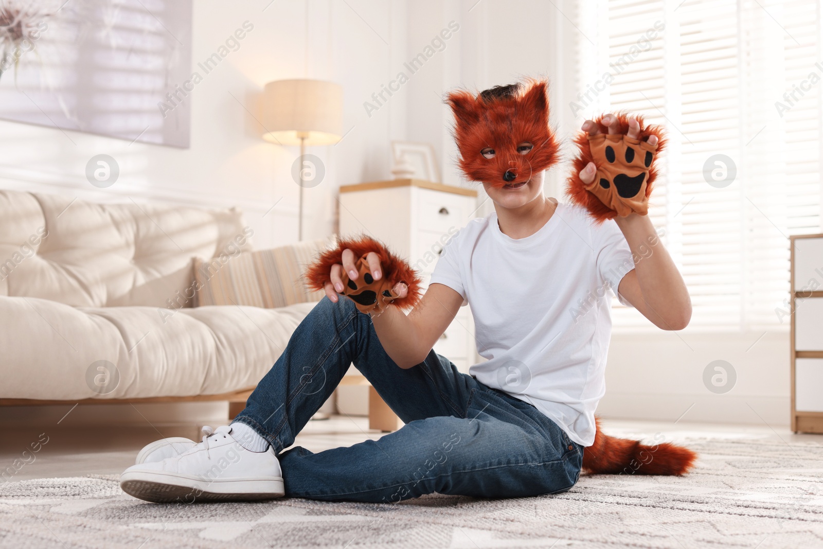 Photo of Quadrobics. Boy wearing fox mask, gloves and tail on floor at home