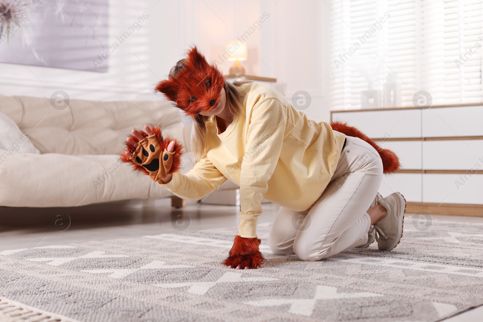 Photo of Quadrobics. Woman wearing fox mask, gloves and tail at home