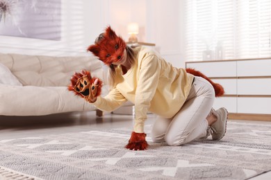 Photo of Quadrobics. Woman wearing fox mask, gloves and tail at home