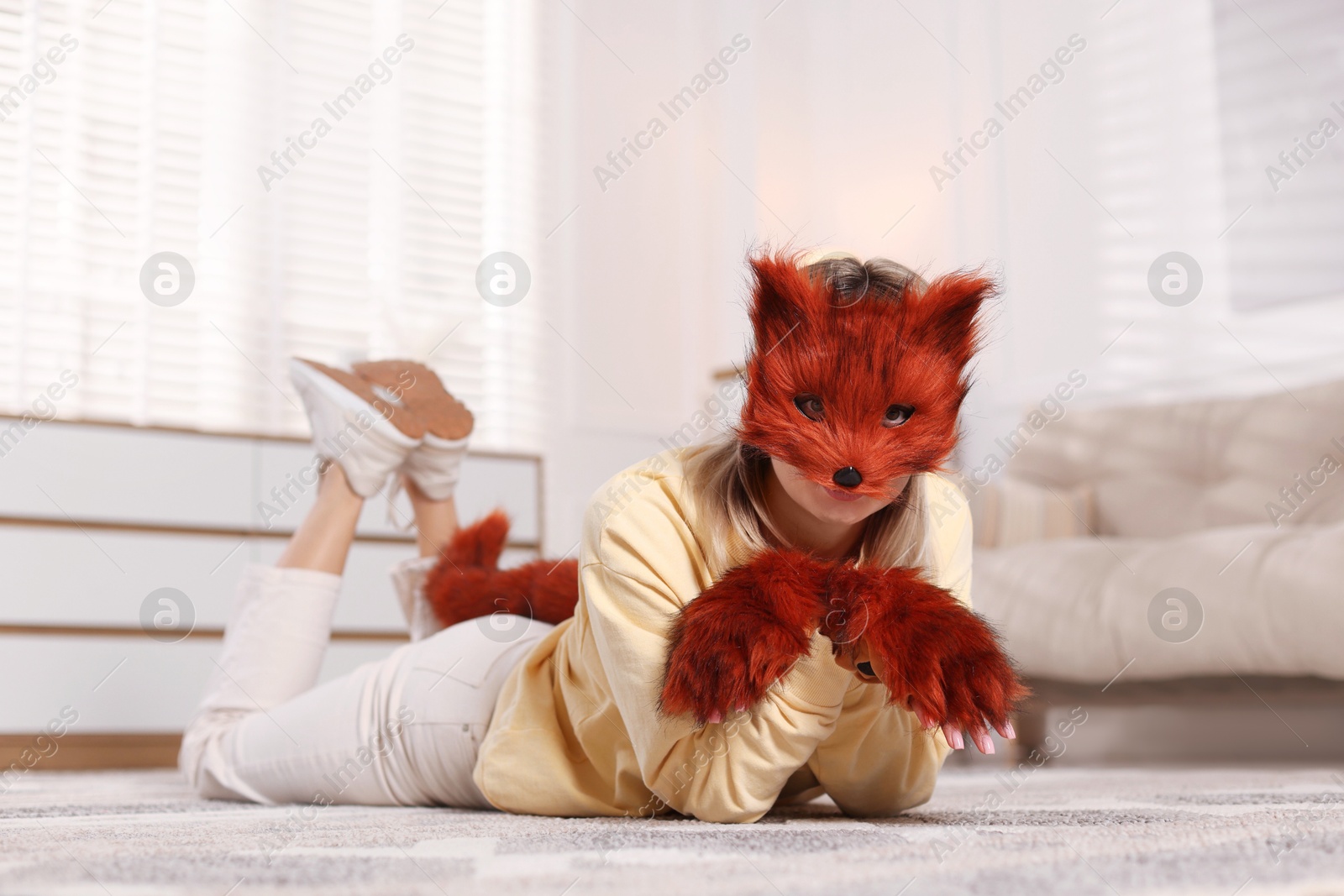 Photo of Quadrobics. Woman wearing fox mask, gloves and tail at home