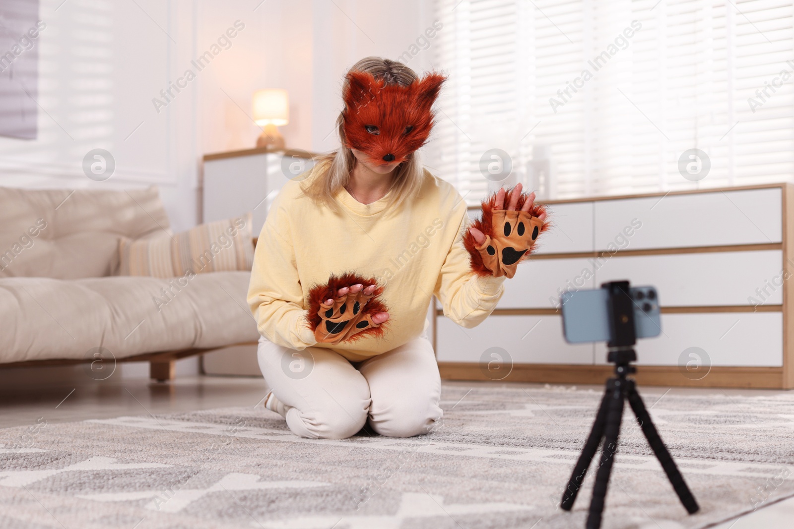 Photo of Quadrobics. Woman in fox mask and gloves recording video at home