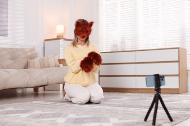 Photo of Quadrobics. Woman in fox mask and gloves recording video at home