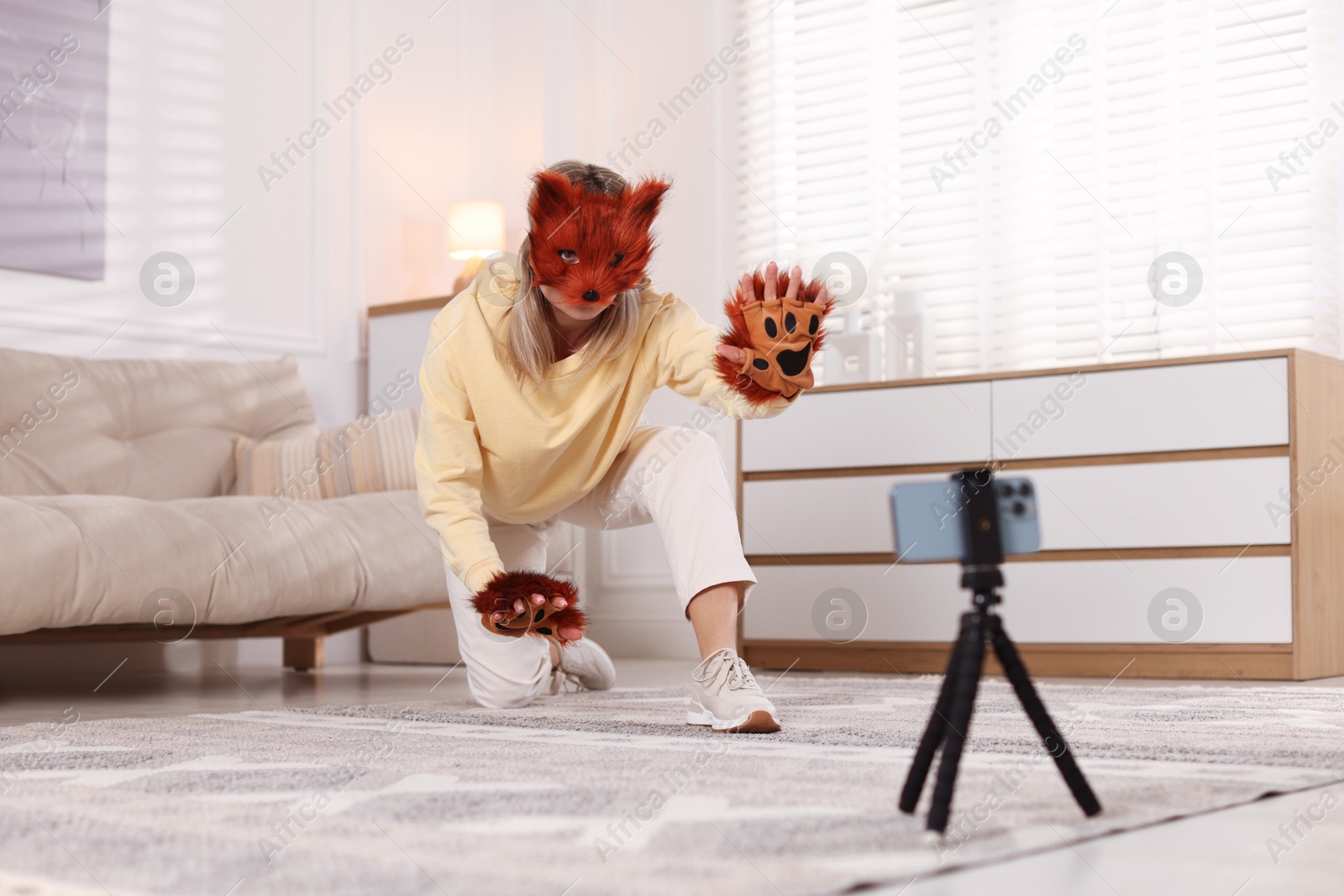 Photo of Quadrobics. Woman in fox mask and gloves recording video at home