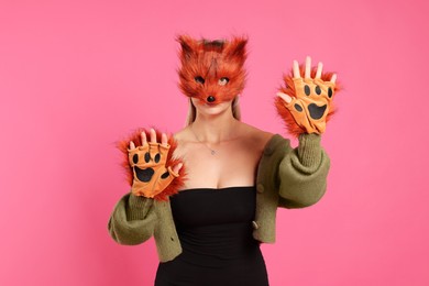 Photo of Quadrobics. Woman wearing fox mask and gloves on pink background