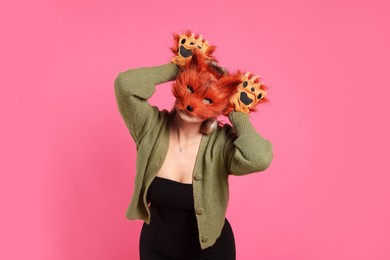 Photo of Quadrobics. Woman wearing fox mask and gloves on pink background