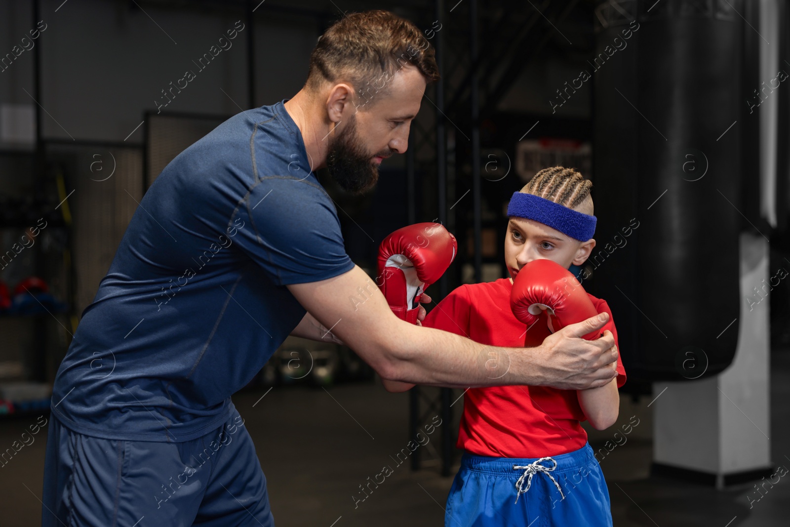 Photo of Boxing coach training boy in sport center