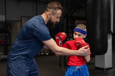 Boxing coach training boy in sport center