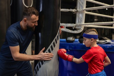 Photo of Boxing coach training boy in sport center