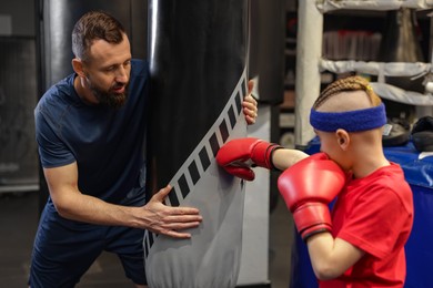 Boxing coach training boy in sport center