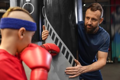 Photo of Boxing coach training boy in sport center