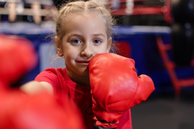 Girl in protective gloves having boxing practice indoors