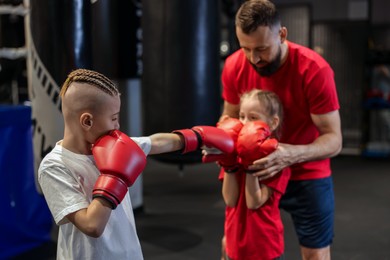 Boxing coach training children in sport center